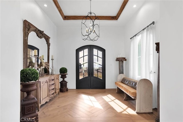 foyer with light parquet flooring, a tray ceiling, a wealth of natural light, and french doors