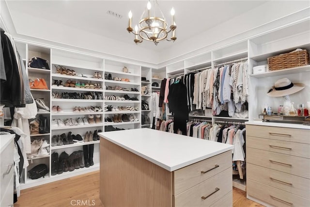 spacious closet featuring a chandelier and light wood-type flooring