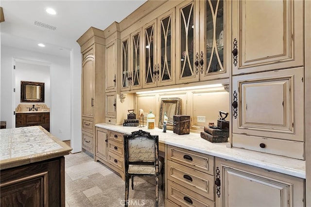 kitchen with light stone counters, sink, and built in desk