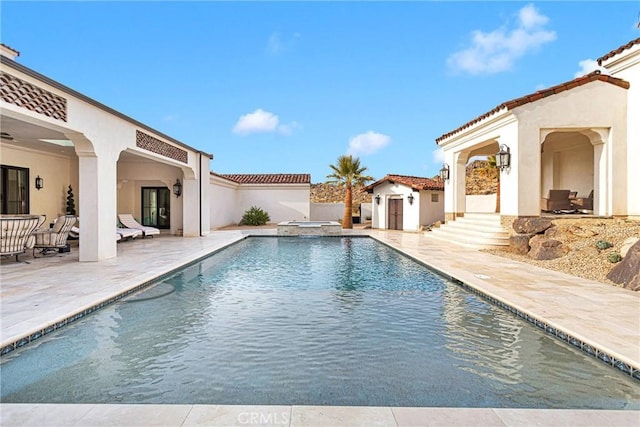 view of pool with an in ground hot tub, an outdoor structure, and a patio area