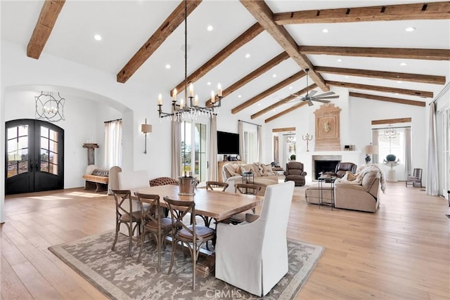 dining room with ceiling fan with notable chandelier, high vaulted ceiling, beamed ceiling, light hardwood / wood-style floors, and french doors