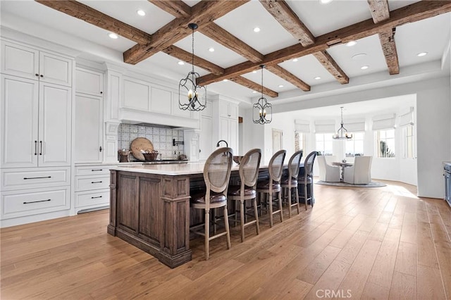 kitchen with hanging light fixtures, a large island, white cabinets, and beamed ceiling