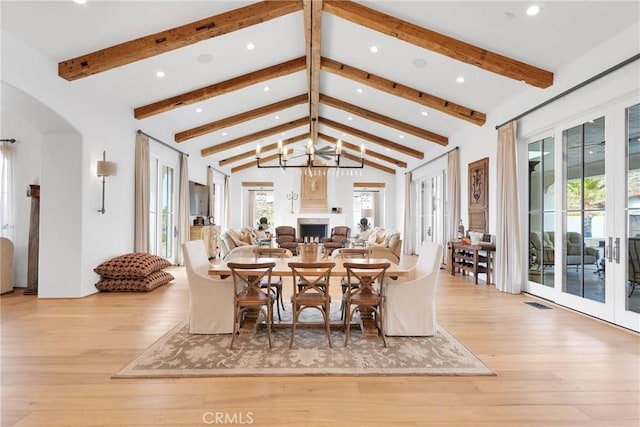 dining area with beam ceiling, french doors, and light wood-type flooring