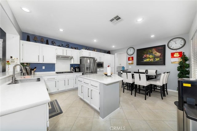 kitchen featuring sink, white cabinets, a center island, light tile patterned floors, and stainless steel appliances