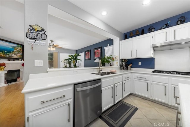 kitchen featuring appliances with stainless steel finishes, white cabinetry, sink, light tile patterned floors, and kitchen peninsula