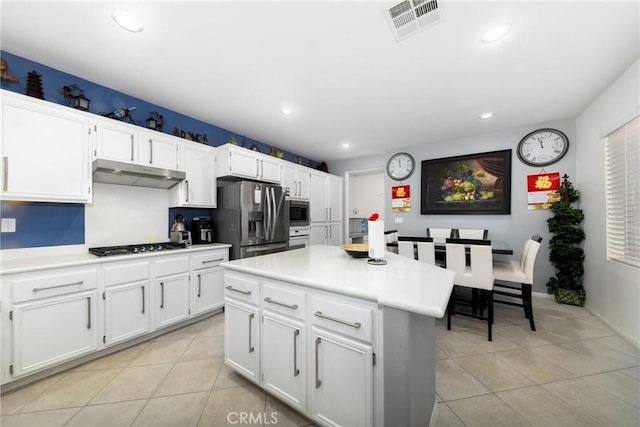 kitchen with white cabinetry, light tile patterned floors, stainless steel appliances, and a kitchen island