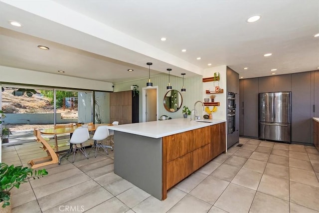 kitchen with stainless steel appliances, kitchen peninsula, hanging light fixtures, and light tile patterned floors