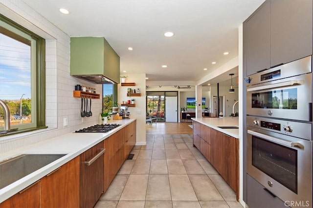 kitchen featuring ventilation hood, appliances with stainless steel finishes, sink, and decorative light fixtures