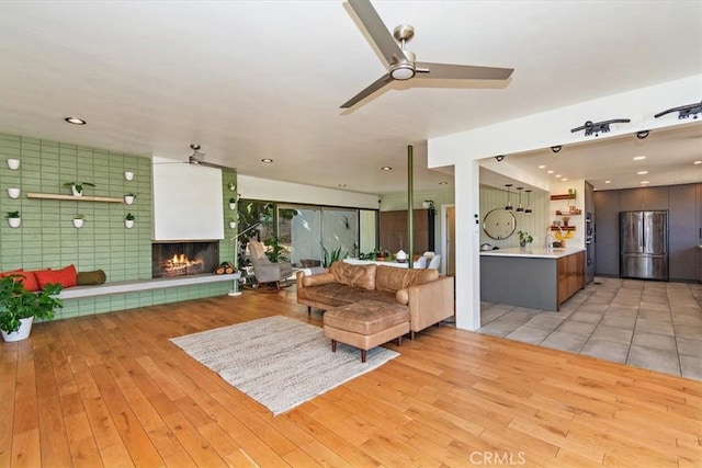 living room featuring a multi sided fireplace, ceiling fan, and light hardwood / wood-style floors