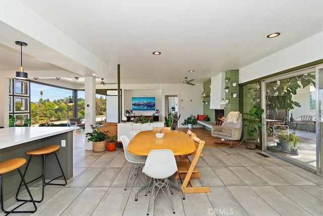 tiled dining area featuring ceiling fan and a large fireplace