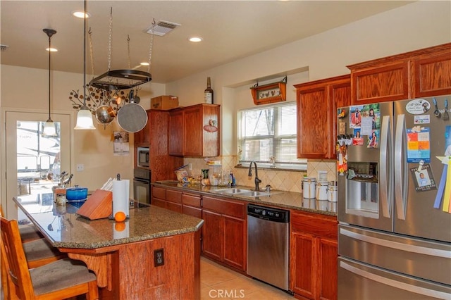 kitchen featuring a kitchen island, appliances with stainless steel finishes, sink, backsplash, and dark stone counters