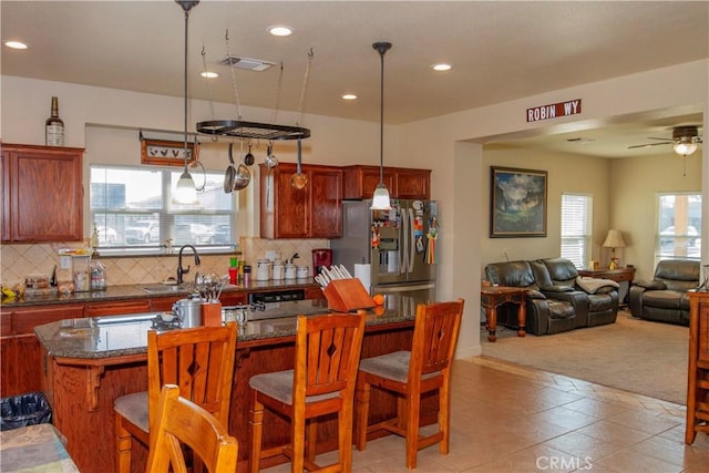 kitchen featuring decorative light fixtures, stainless steel fridge with ice dispenser, a breakfast bar area, and backsplash