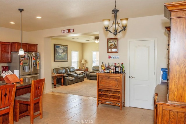 dining area with light tile patterned flooring and ceiling fan with notable chandelier