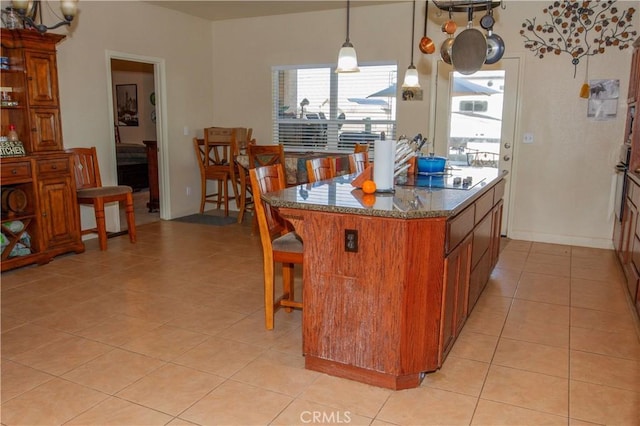 kitchen featuring decorative light fixtures, a breakfast bar, a kitchen island, and dark stone countertops