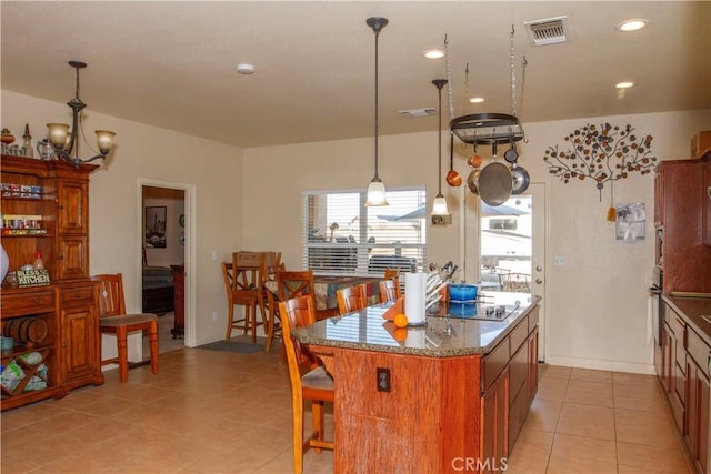 kitchen featuring a kitchen breakfast bar, hanging light fixtures, a center island, black electric stovetop, and light tile patterned floors