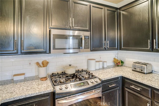 kitchen featuring light stone counters, stainless steel appliances, and decorative backsplash