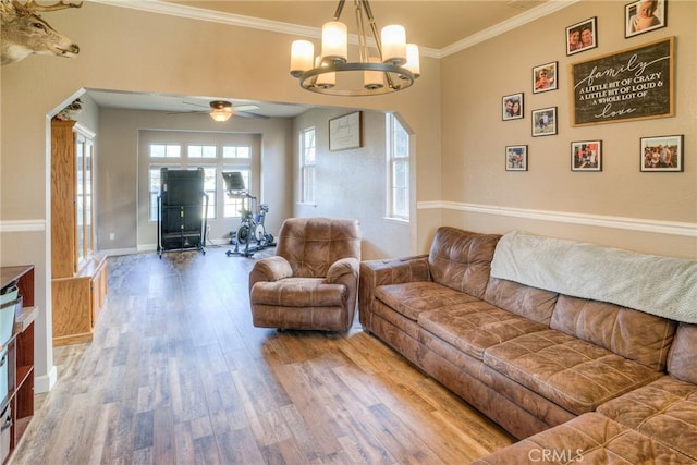 living room featuring crown molding, wood-type flooring, and ceiling fan with notable chandelier