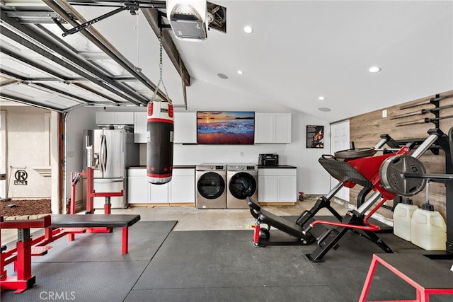 exercise room featuring lofted ceiling, wooden walls, and washer and dryer