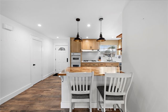 kitchen featuring a breakfast bar area, gas cooktop, kitchen peninsula, double oven, and pendant lighting