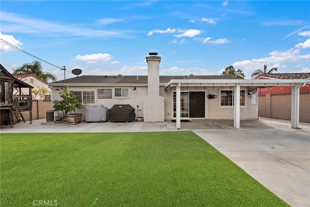 rear view of house featuring central AC unit, a lawn, and a patio