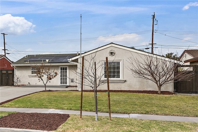 view of front of home featuring solar panels and a front lawn