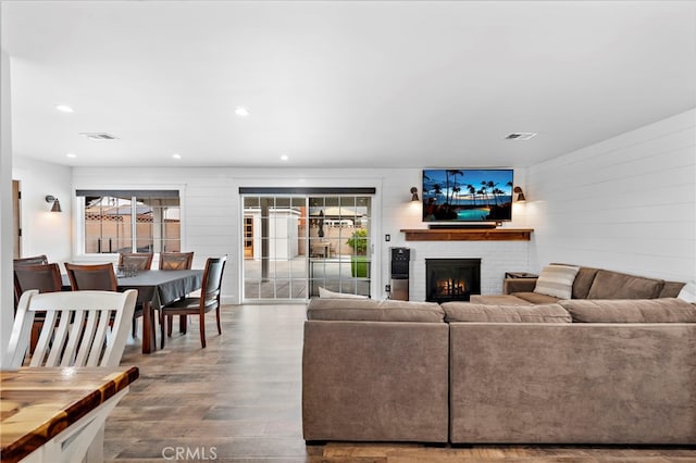 living room featuring wood-type flooring and a brick fireplace