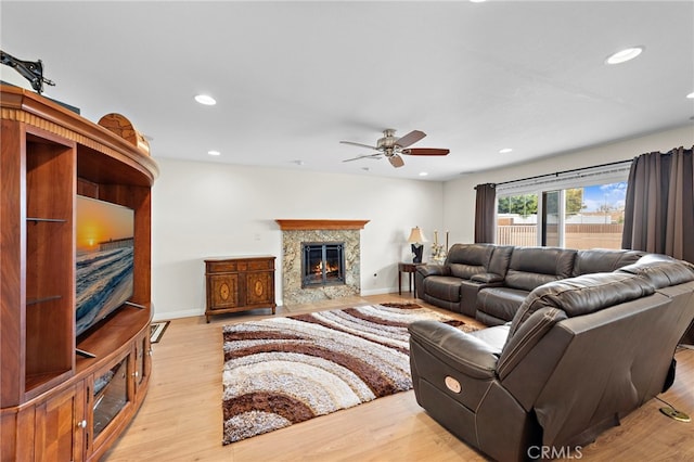 living room with ceiling fan, a premium fireplace, and light wood-type flooring