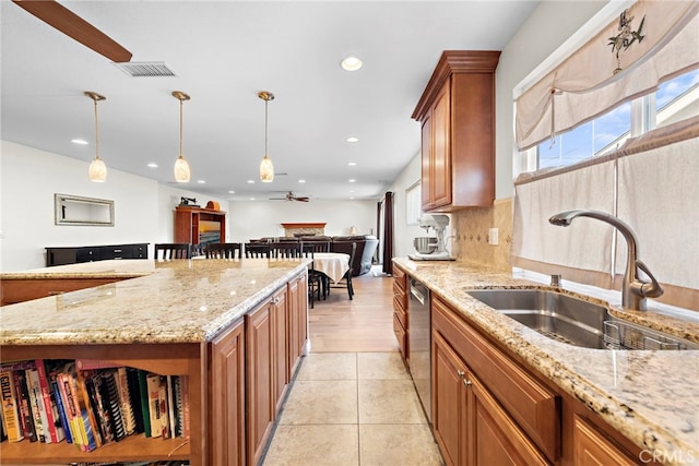 kitchen featuring sink, light stone counters, decorative light fixtures, dishwasher, and decorative backsplash