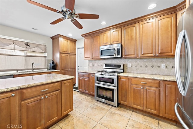 kitchen featuring sink, light tile patterned floors, stainless steel appliances, light stone countertops, and backsplash