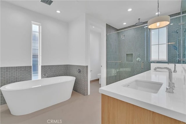 full bathroom with vanity, toilet, independent shower and bath, and tile walls