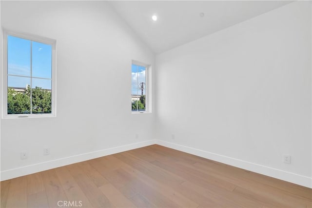 unfurnished room with vaulted ceiling and light hardwood / wood-style flooring