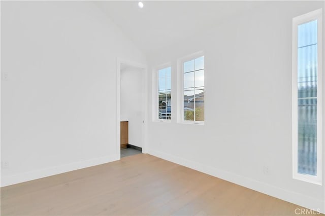 unfurnished room featuring lofted ceiling and light wood-type flooring