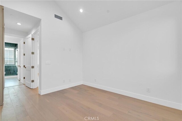 spare room featuring lofted ceiling and light wood-type flooring