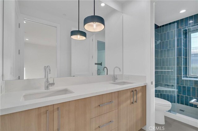 bathroom featuring tiled shower, vanity, and toilet