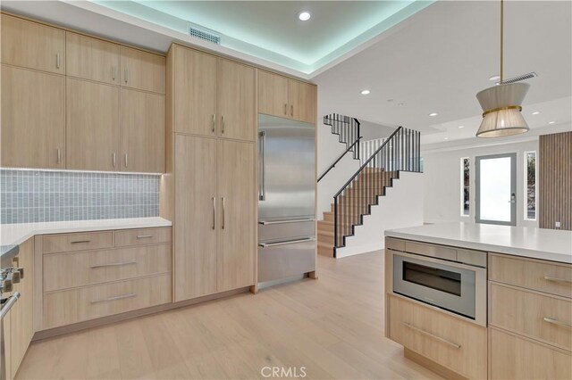 kitchen with built in appliances, light brown cabinetry, and light hardwood / wood-style flooring