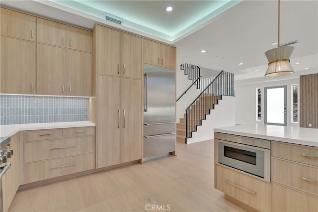 kitchen featuring built in appliances, light hardwood / wood-style floors, and light brown cabinets