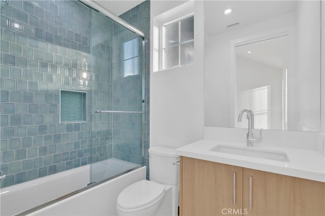 full bathroom featuring vanity, shower / bath combination with glass door, and toilet