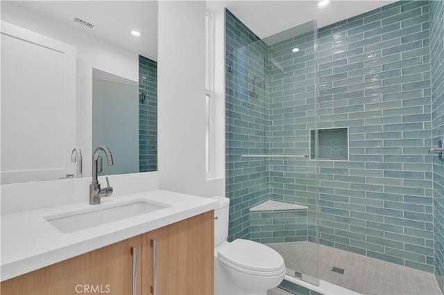 bathroom with vanity, toilet, and tiled shower