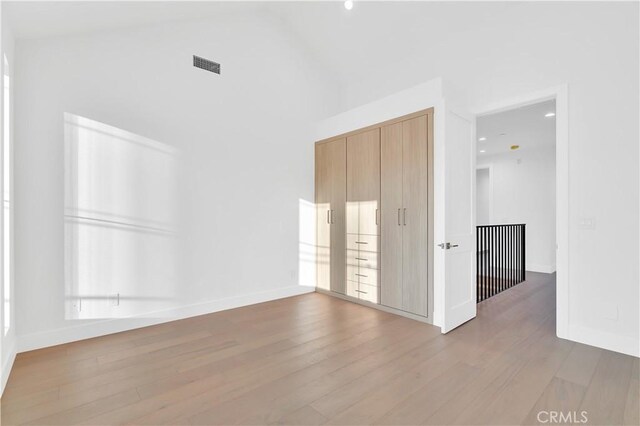 empty room with a towering ceiling and wood-type flooring