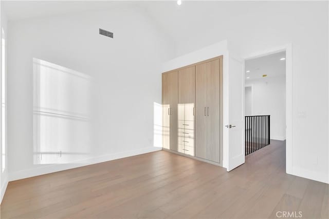 unfurnished bedroom with wood-type flooring and a high ceiling