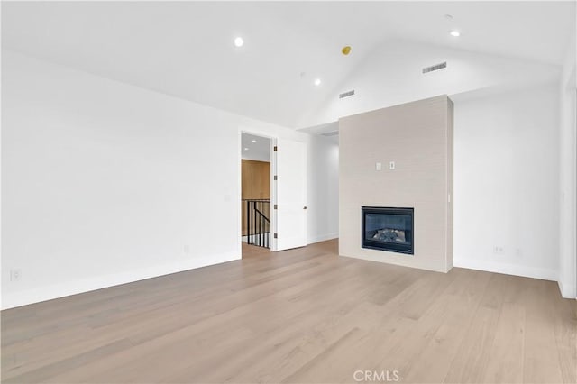 unfurnished living room with a large fireplace, high vaulted ceiling, and light hardwood / wood-style floors