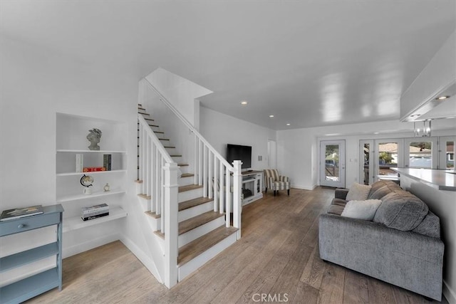 living area with hardwood / wood-style flooring, baseboards, french doors, and stairs