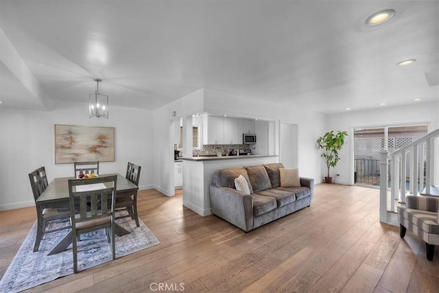 dining room featuring a chandelier, light wood finished floors, recessed lighting, and baseboards