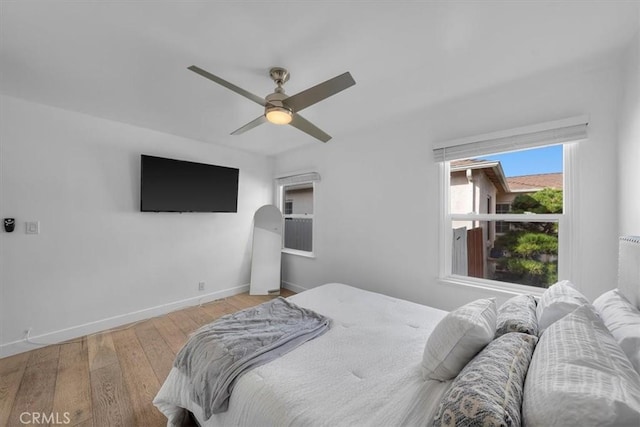 bedroom with hardwood / wood-style floors, a ceiling fan, and baseboards