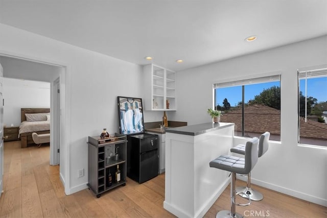 kitchen featuring light wood-type flooring, dark countertops, a breakfast bar area, and white cabinets