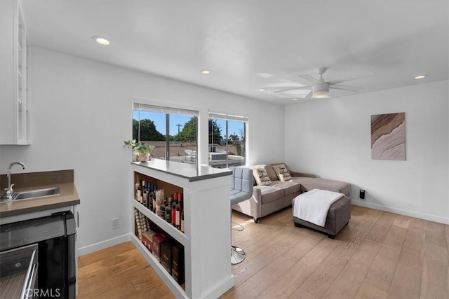 living room featuring sink, ceiling fan, and light hardwood / wood-style flooring