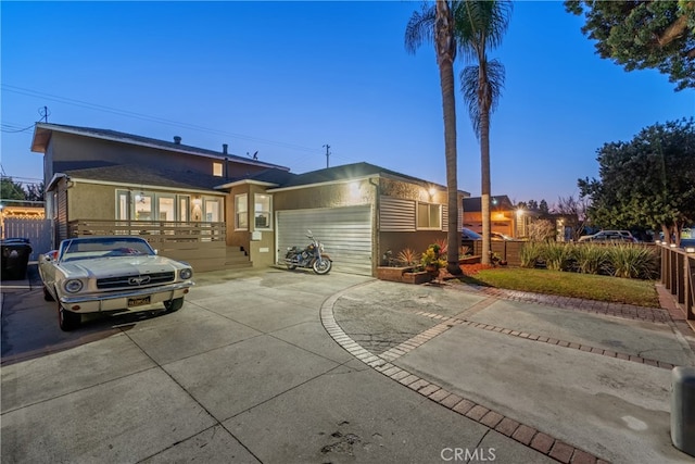 ranch-style house with stucco siding, an attached garage, concrete driveway, and fence