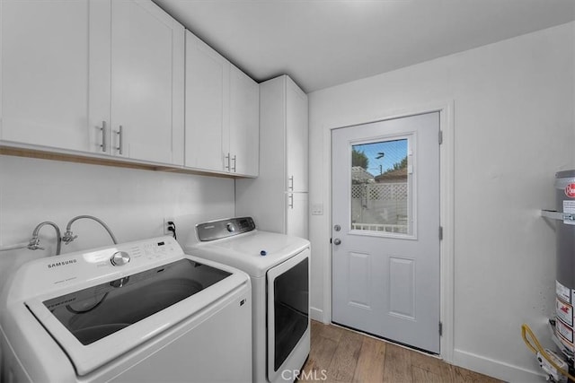 laundry area featuring cabinet space, baseboards, wood finished floors, washing machine and dryer, and water heater