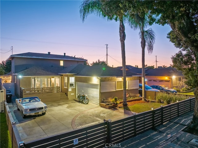 back of property with driveway, a fenced front yard, and stucco siding