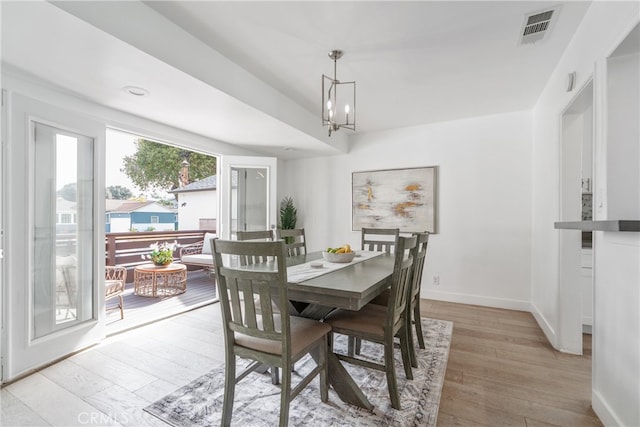 dining space featuring baseboards, a notable chandelier, visible vents, and light wood-type flooring